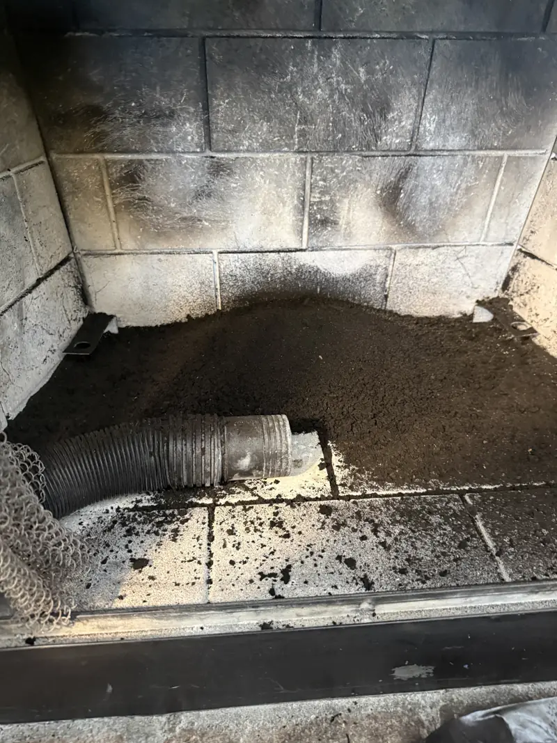 Fireplace firebox before cleaning, with soot and debris