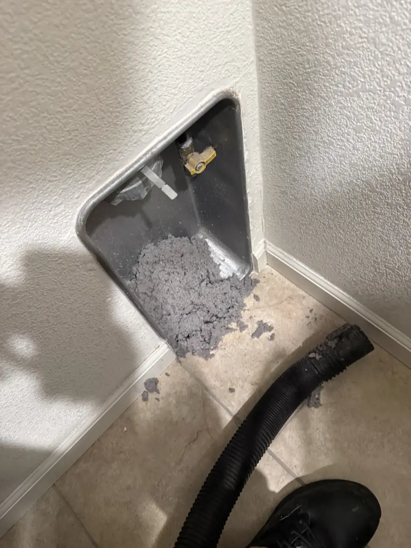 Lint built up behind a dryer at the wall vent connection