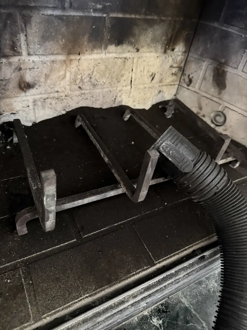 Fireplace firebox during cleaning with protective vacuum hose