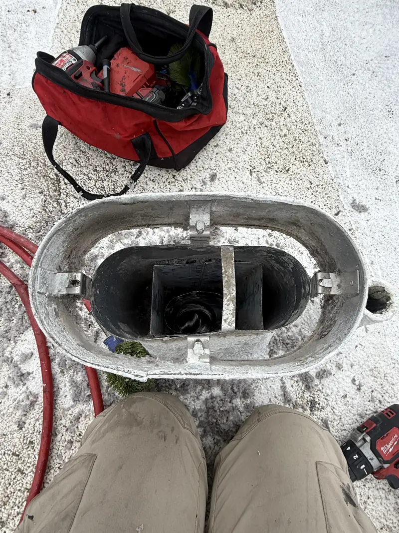 Rooftop dryer vent hood after cleaning, with tool bag nearby
